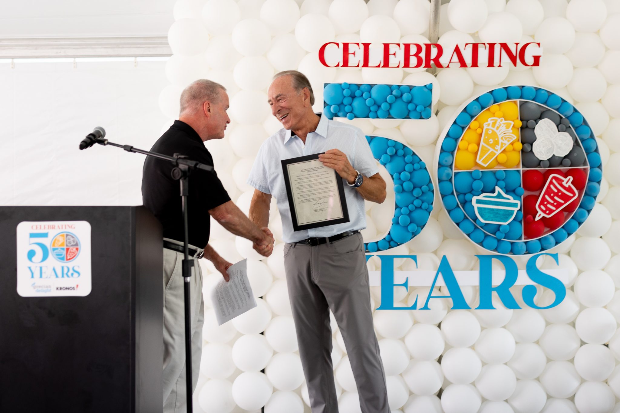 Peter Parthenis Sr, former CEO and founder of Grecian Delight, accepts an award on behalf of Grecian Delight Kronos for celebrating their 50 years in business.